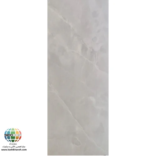  سرامیک آتریا براق کاشی صدیق سرام آباده  معرفی سرامیک آتریا براق کاشی صدیق سرام آباده سرامیک آتریا براق کاشی صدیق سرام آباده یکی از محصولات زیبا و کاربردی برای پوشش دیوارهای داخلی ساختمان است که با الهام از بافت سنگ طبیعی طراحی شده و ظاهری آرام، مدرن و لوکس به محیط می‌بخشد. همان‌طور که در تصویر محصول مشاهده می‌شود، زمینه طوسی روشن مایل به کرم همراه با رگه‌های طبیعی و نامنظم، جلوه‌ای نزدیک به سنگ‌های طبیعی ایجاد کرده است. این طراحی باعث می‌شود فضای داخلی بدون شلوغی بصری، حس نظم، آرامش و زیبایی بیشتری پیدا کند. استفاده از چنین طرحی در سال‌های اخیر به یکی از محبوب‌ترین انتخاب‌های معماران و طراحان داخلی تبدیل شده است، زیرا علاوه بر ظاهر زیبا، با بسیاری از سبک‌های معماری هماهنگی دارد. ابعاد 80×40 سانتی‌متر این سرامیک باعث می‌شود تعداد بندهای اجرا کاهش پیدا کند و سطح دیوار یکپارچه‌تر دیده شود. این ویژگی علاوه بر افزایش زیبایی، سرعت نصب را نیز بیشتر می‌کند. بدنه خاک قرمز این محصول کیفیت مناسبی برای استفاده در دیوارهای داخلی فراهم کرده و به دلیل ساختار استاندارد خود، انتخابی اقتصادی و کاربردی برای پروژه‌های ساختمانی محسوب می‌شود. همچنین لعاب براق به کار رفته روی سطح سرامیک، نور محیط را منعکس کرده و باعث می‌شود فضا روشن‌تر، بزرگ‌تر و دل‌بازتر به نظر برسد.