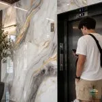 سرامیک خاک سفید آرسان براق کاشی ماهان سرام سرامیک خاک سفید آرسان براق کاشی ماهان سرام با ابعاد 120×60 سانتیمتر، دارای زمینهای روشن با رگههای طوسی و خطوط طلایی است. ترکیب این رنگها، جلوهای شبیه به سنگهای طبیعی ایجاد میکند و میتواند برای فضاهایی با طراحی مدرن، کلاسیک معاصر یا لوکس مورد توجه قرار گیرد. درسرامیک خاک سفید آرسان براق کاشی ماهان سرام، زمینه سفید در کنار بخشهای خاکستری و رگههای طلایی قرار گرفته است. این ترکیب رنگی امکان هماهنگی با متریالهایی مانند چوب، فلزات طلایی، شیرآلات کروم، مبلمان کرم و عناصر دکوراتیو مشکی را فراهم میکند. البته انتخاب سرامیک مناسب فقط به هماهنگی رنگها محدود نمیشود. محل نصب، میزان رفتوآمد، مقاومت سطح، شرایط رطوبتی، کیفیت زیرسازی و روش اجرا نیز باید در نظر گرفته شوند. در ادامه، ویژگیها و کاربردهای سرامیک خاک سفید آرسان براق کاشی ماهان سرام را بررسی میکنیم تا بتوانید با اطلاعات بیشتری درباره خرید آن تصمیم بگیرید. انتخاب پوشش مناسب برای کف و دیوار، یکی از مراحل مهم در طراحی داخلی ساختمان است. رنگ، طرح، ابعاد و نوع سطح سرامیک میتوانند تأثیر قابل توجهی بر ظاهر نهایی محیط داشته باشند. به همین دلیل، هنگام خرید سرامیک بهتر است علاوه بر قیمت و زیبایی، شرایط استفاده و ویژگیهای فنی سرامیک خاک سفید آرسان براق کاشی ماهان سرام را نیز بررسی کنیم.